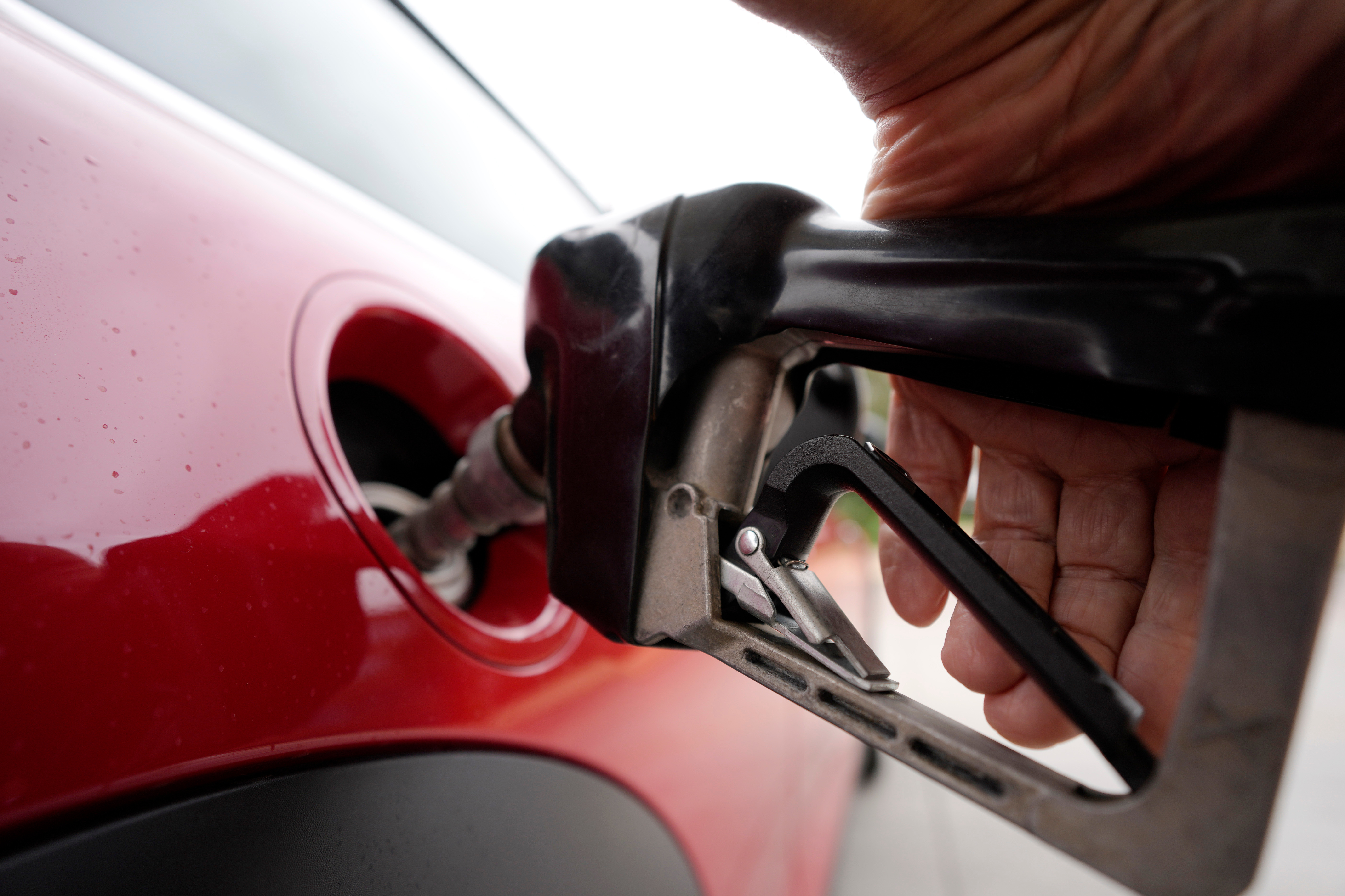 Red fuel pump nozzle being inserted into a vehicle's red fuel door opening