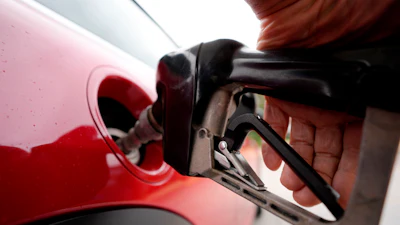 Red fuel pump nozzle being inserted into a vehicle's red fuel door opening