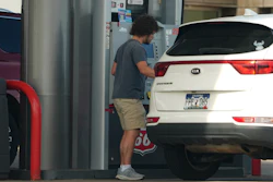 Person standing at parking garage next to white KIA Sportage SUV with license plate visible
