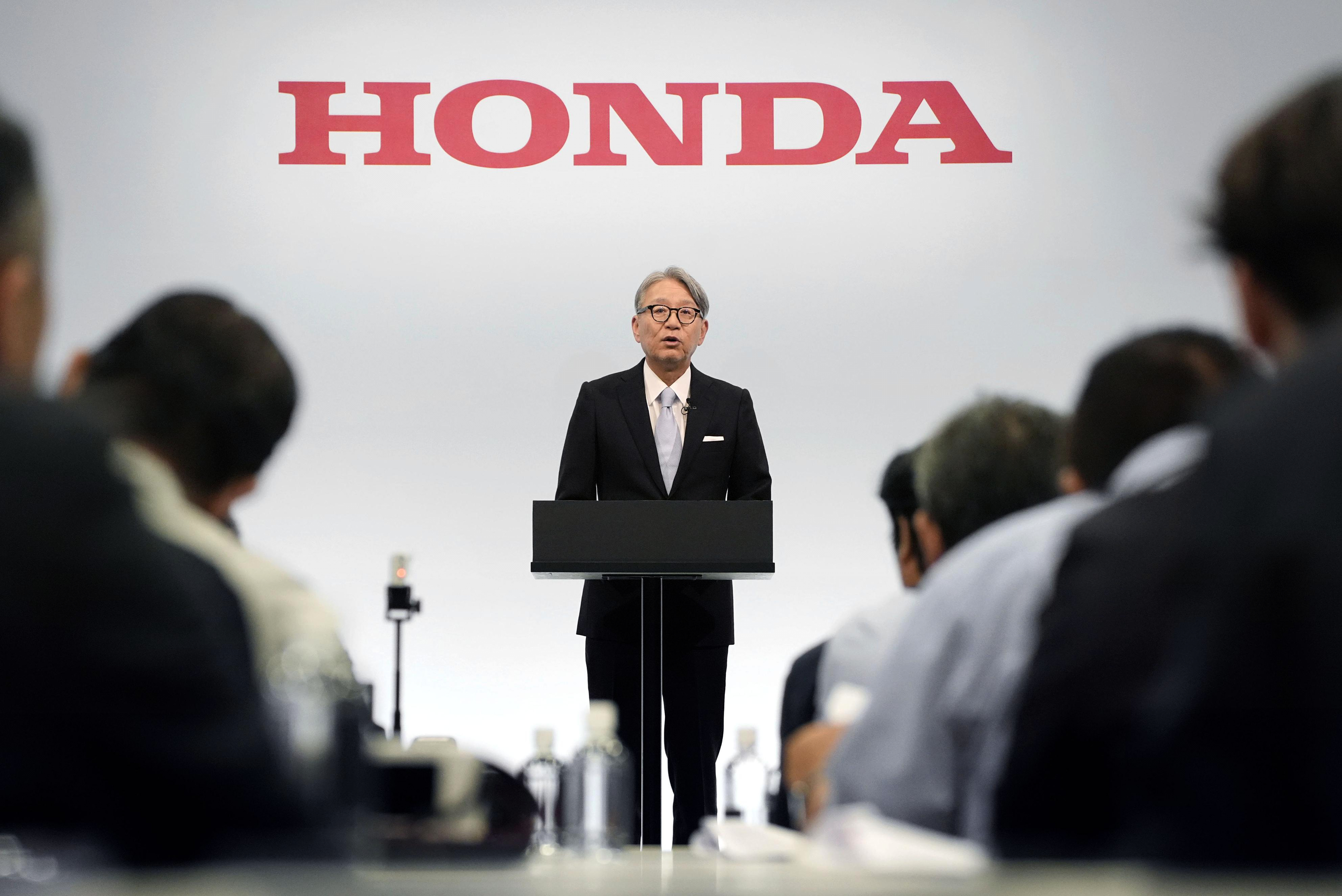 Honda executive speaking at podium during corporate press conference with attendees seated