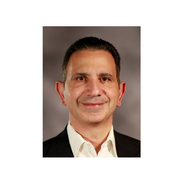 Professional headshot of a middle-aged man in business attire with dark hair and a friendly smile