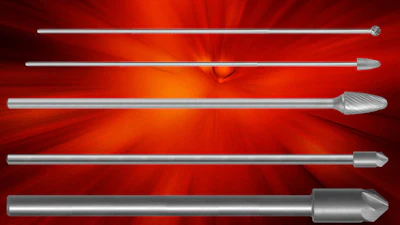 Five metallic industrial cutting bits and burrs arranged horizontally on red background