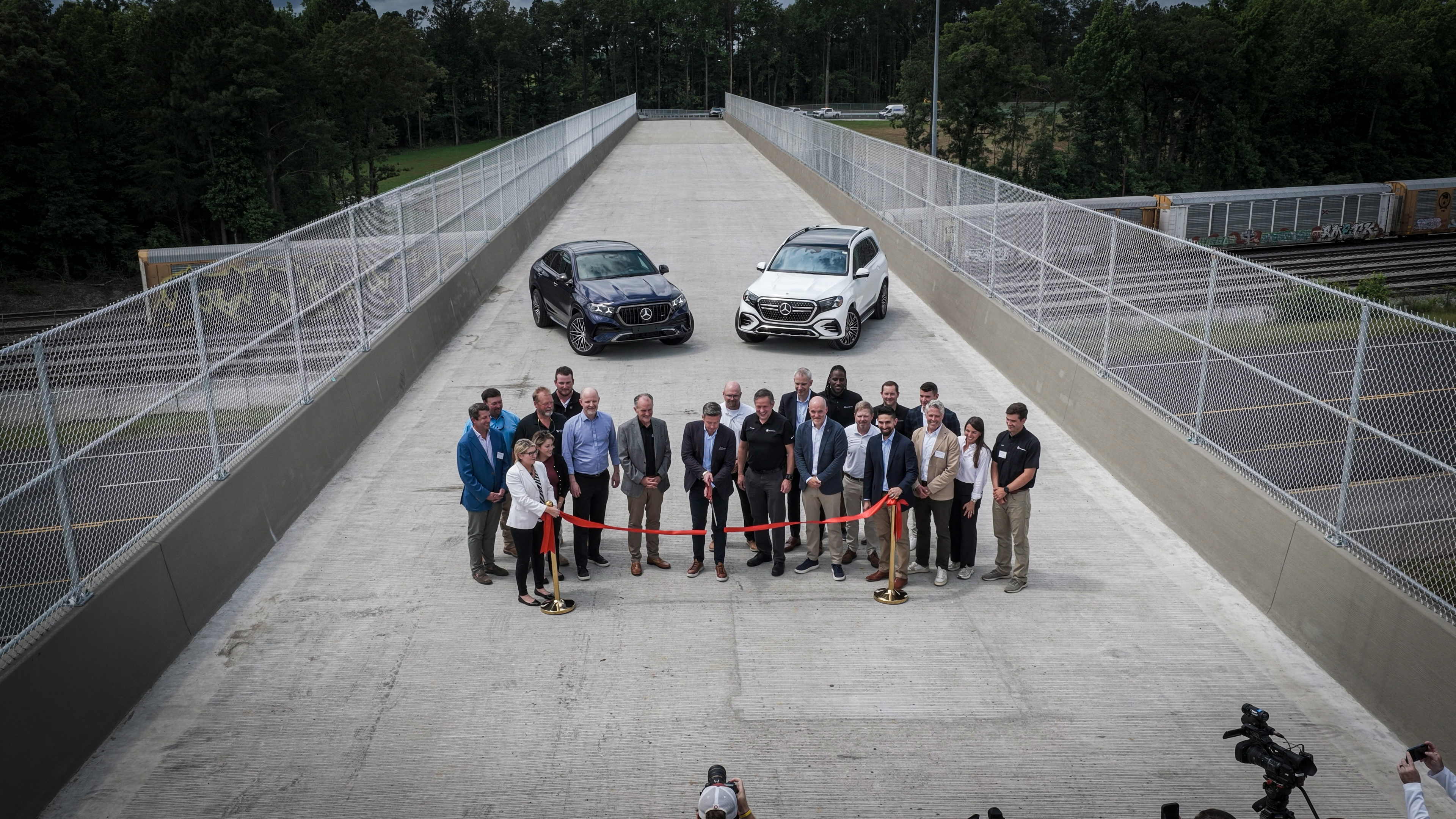 Corporate event with group of professionals and two vehicles on elevated bridge platform