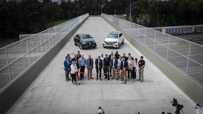Corporate event with group of professionals and two vehicles on elevated bridge platform