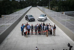 Corporate event with group of professionals and two vehicles on elevated bridge platform
