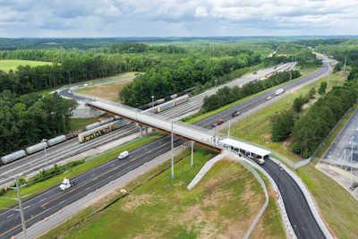 Aerial view of multi-level highway interchange with bridges, vehicles, and surrounding green forest landscape