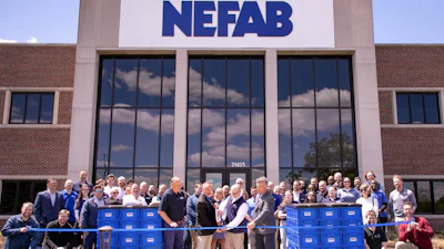 Large group of NEFAB employees gathered for ribbon-cutting ceremony in front of company headquarters with blue crates