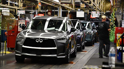 Infiniti luxury vehicles on assembly line in manufacturing plant with workers and industrial equipment