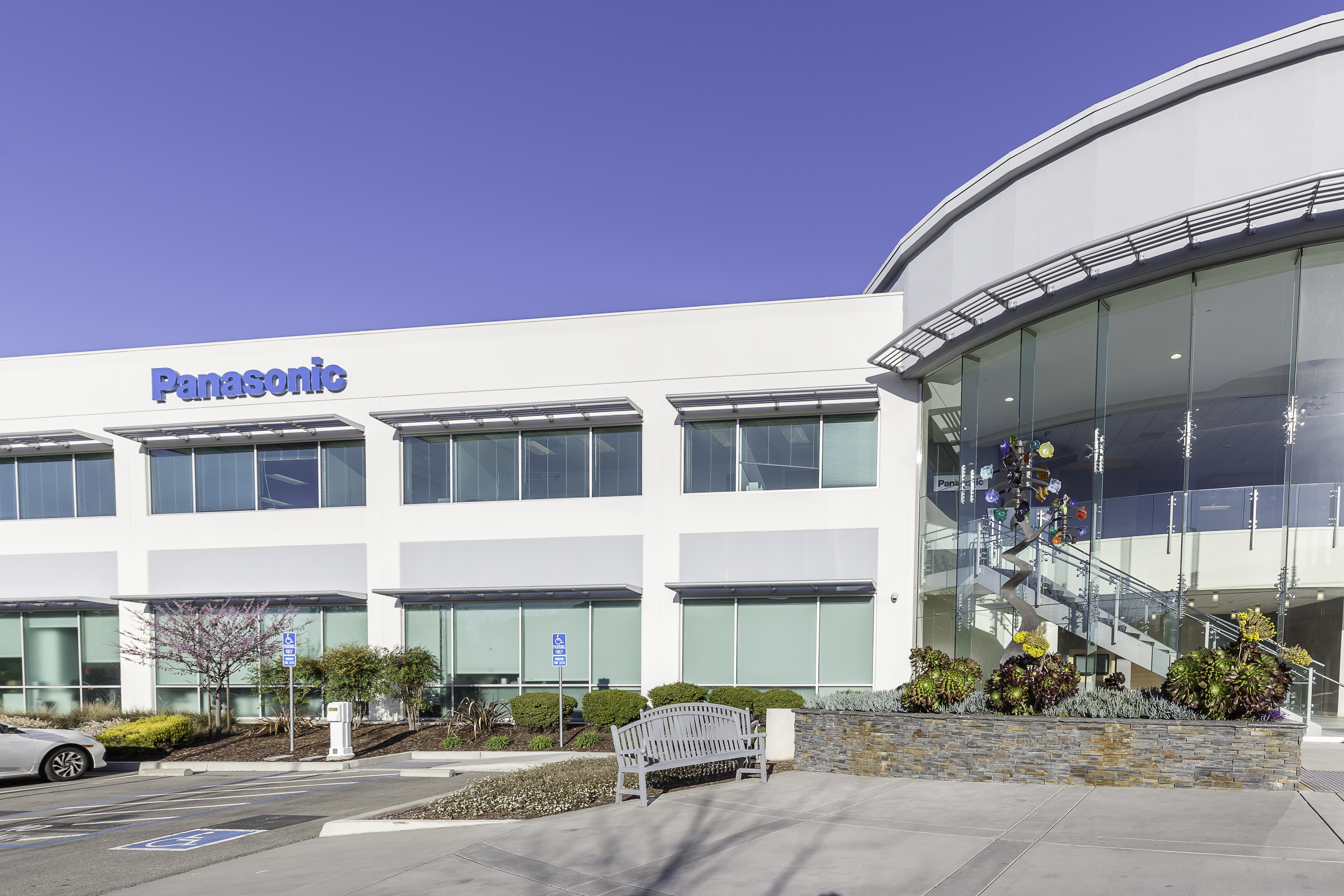Panasonic corporate office building with modern white facade and curved glass entrance under clear blue sky