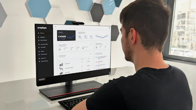 Man viewing analytics dashboard on computer monitor in modern office with hexagonal wall panels