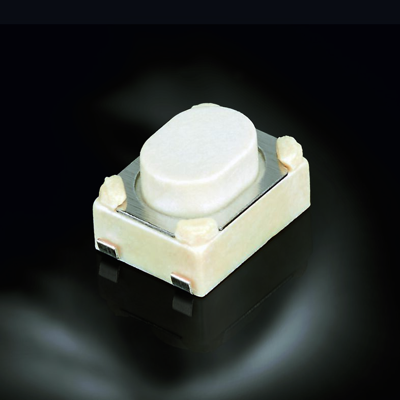 White tactile push button switch with metallic contact plate on dark background