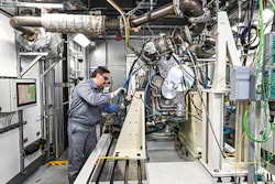 Technician working on industrial machinery and piping systems in a manufacturing facility
