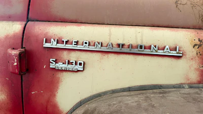 Vintage International Harvester S-130 Series truck badging on weathered red and cream painted vehicle door