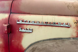 Vintage International Harvester S-130 Series truck badging on weathered red and cream painted vehicle door