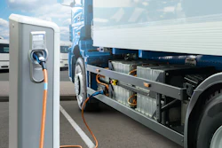 Electric vehicle charging station with orange cable connected to blue and white truck at commercial fleet facility