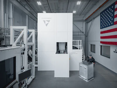 Industrial manufacturing facility with white modular equipment structure displaying Divergent logo, American flag visible on wall