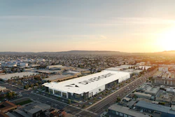 Aerial view of large white industrial facility with corporate signage in suburban landscape at sunset