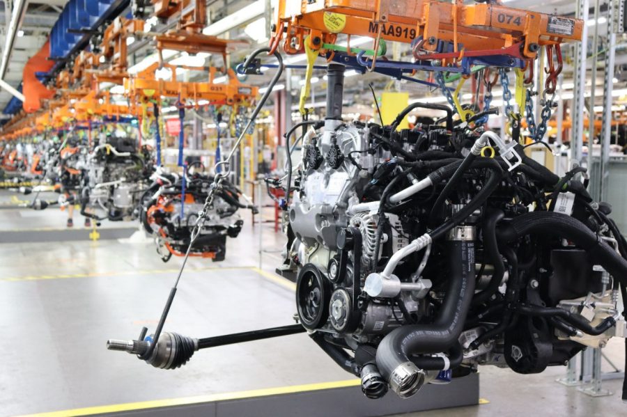 Engine assembly production line in automotive manufacturing facility with orange overhead cranes and industrial equipment