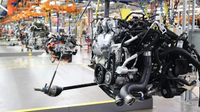 Engine assembly production line in automotive manufacturing facility with orange overhead cranes and industrial equipment