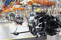 Engine assembly production line in automotive manufacturing facility with orange overhead cranes and industrial equipment