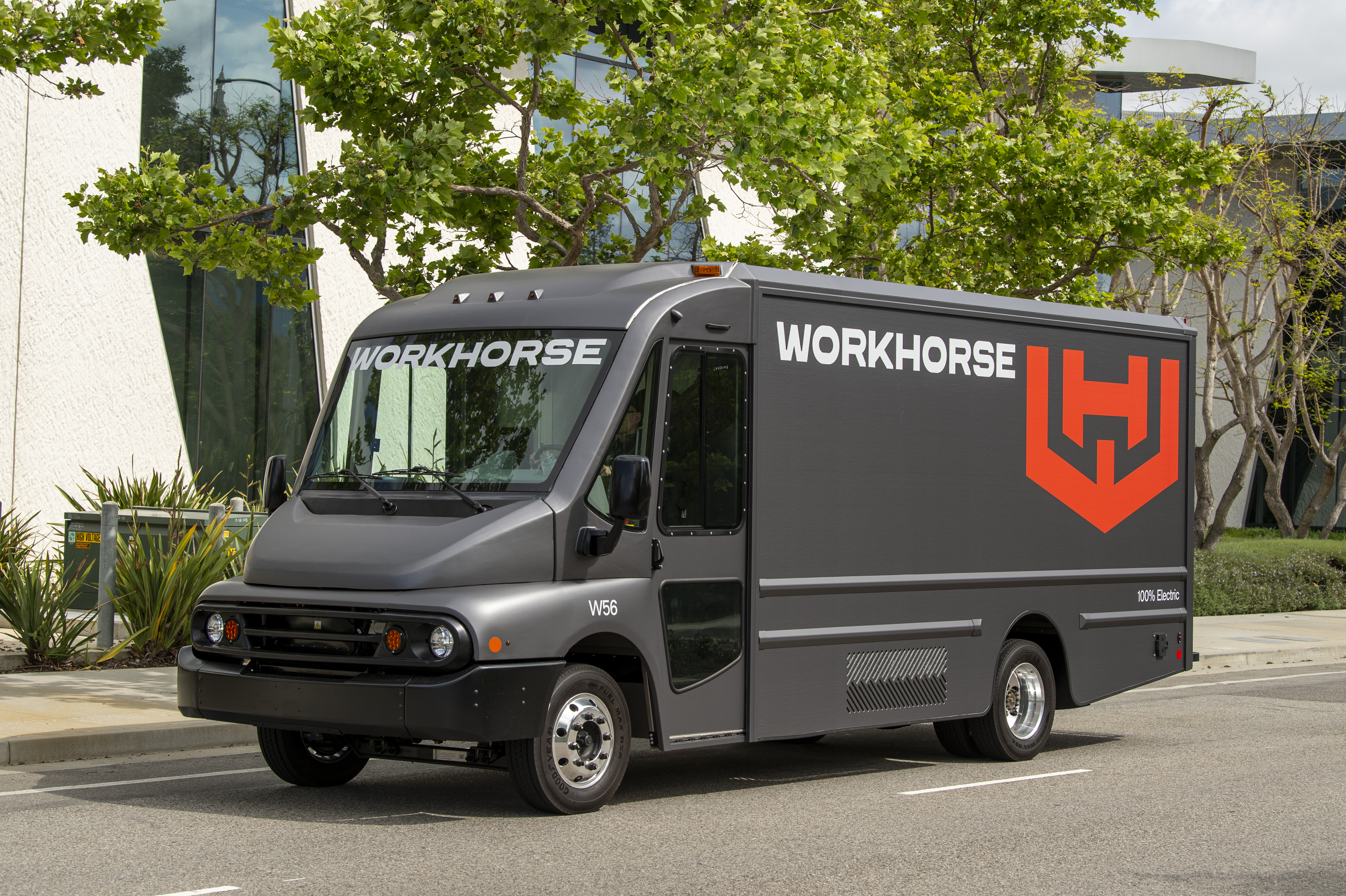 Gray Workhorse electric delivery truck with red logo parked on urban street with trees