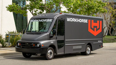 Gray Workhorse electric delivery truck with red logo parked on urban street with trees