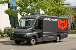 Gray Workhorse electric delivery truck with red logo parked on urban street with trees
