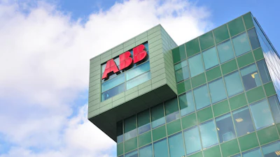ABB red logo on modern green glass office building facade against blue sky
