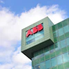ABB red logo on modern green glass office building facade against blue sky