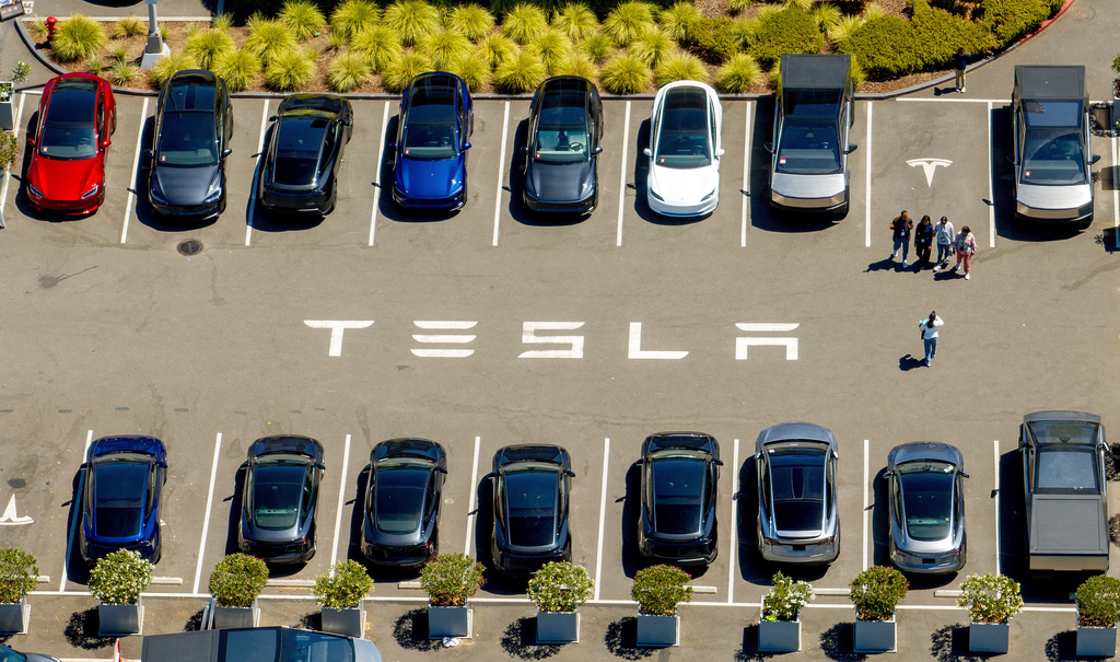 Aerial view of Tesla parking lot with multiple electric vehicles and ground branding
