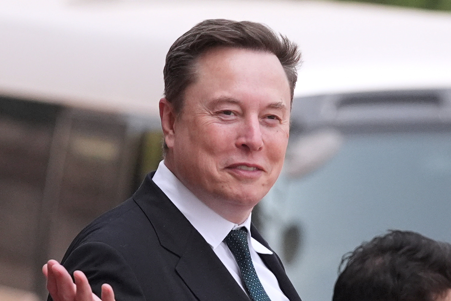 Professional man in dark business suit and tie gesturing while speaking outdoors