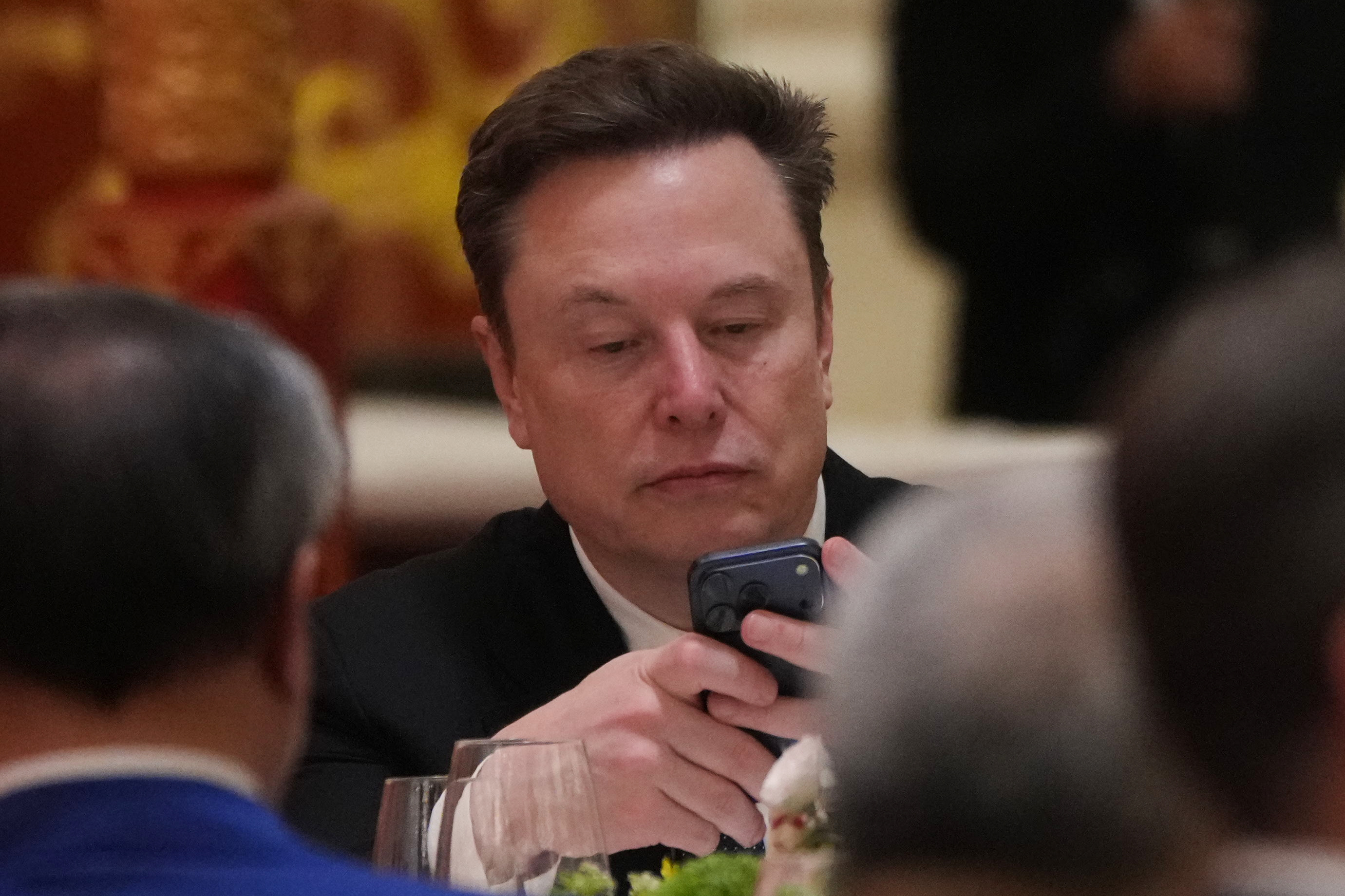 Man in business suit reviewing smartphone during formal meeting or event