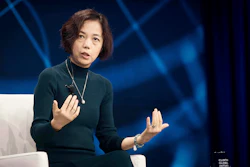 Professional woman speaking at conference with blue abstract background