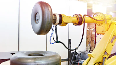 Industrial robotic arm with yellow joints and mechanical components holding a tire in a testing facility