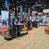 Trade show exhibition floor with multiple vendor booths, equipment displays, and overhead signage including Novanta and Edmund branding.