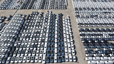 Aerial view of large vehicle storage lot with hundreds of cars arranged in organized rows on concrete surface