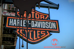 Harley-Davidson orange and black shield logo on storefront sign with clear blue sky