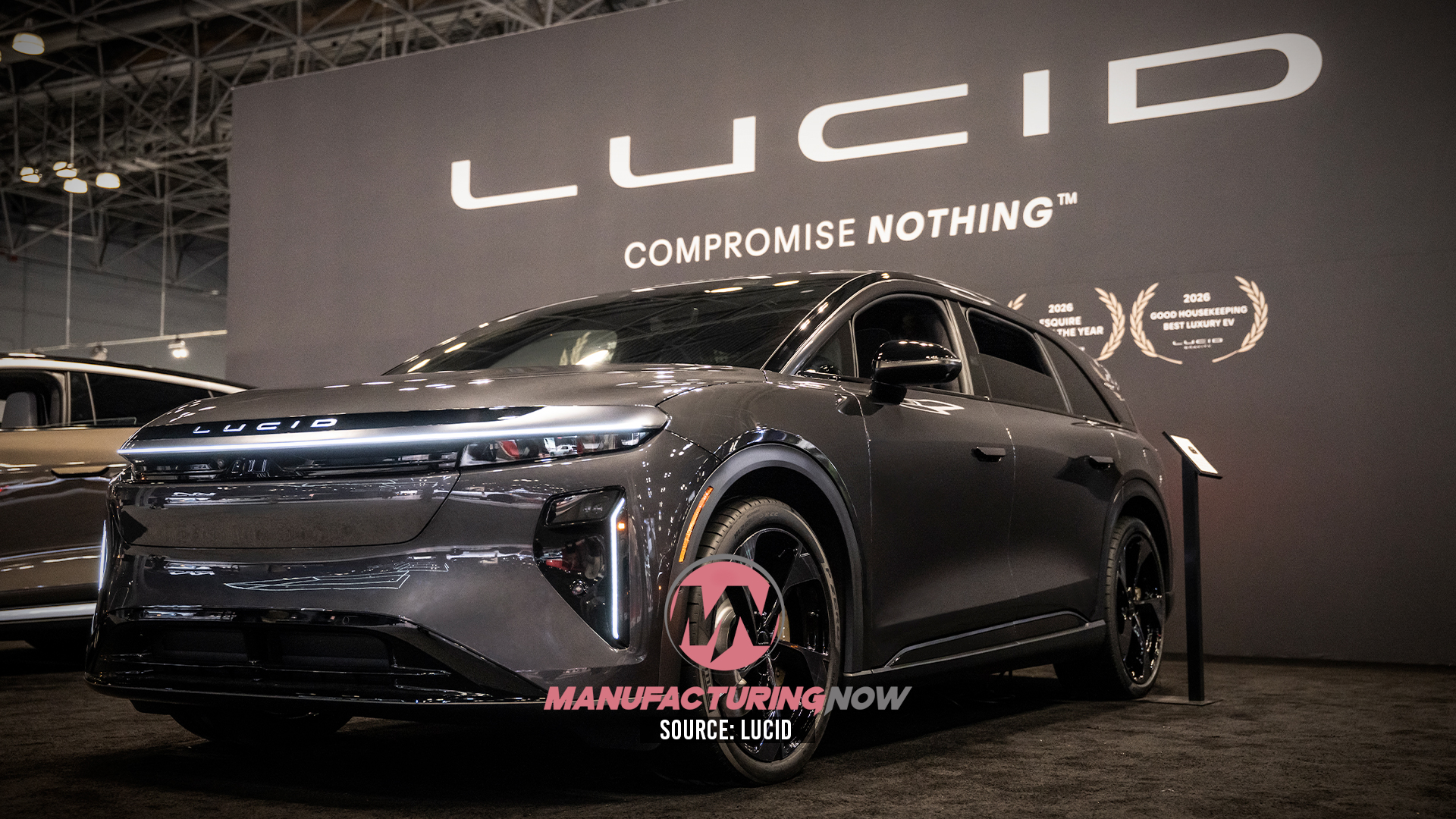 Lucid electric SUV displayed at automotive showroom with 'Compromise Nothing' brand tagline on backdrop