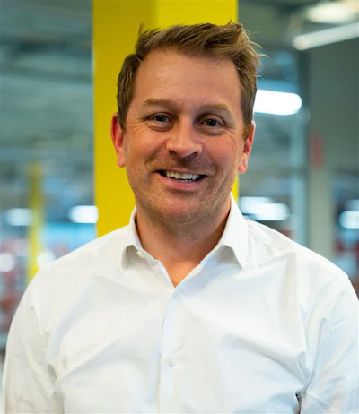 Professional man smiling in white shirt against yellow office column