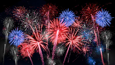 Colorful fireworks exploding in night sky with red, blue, and white bursts
