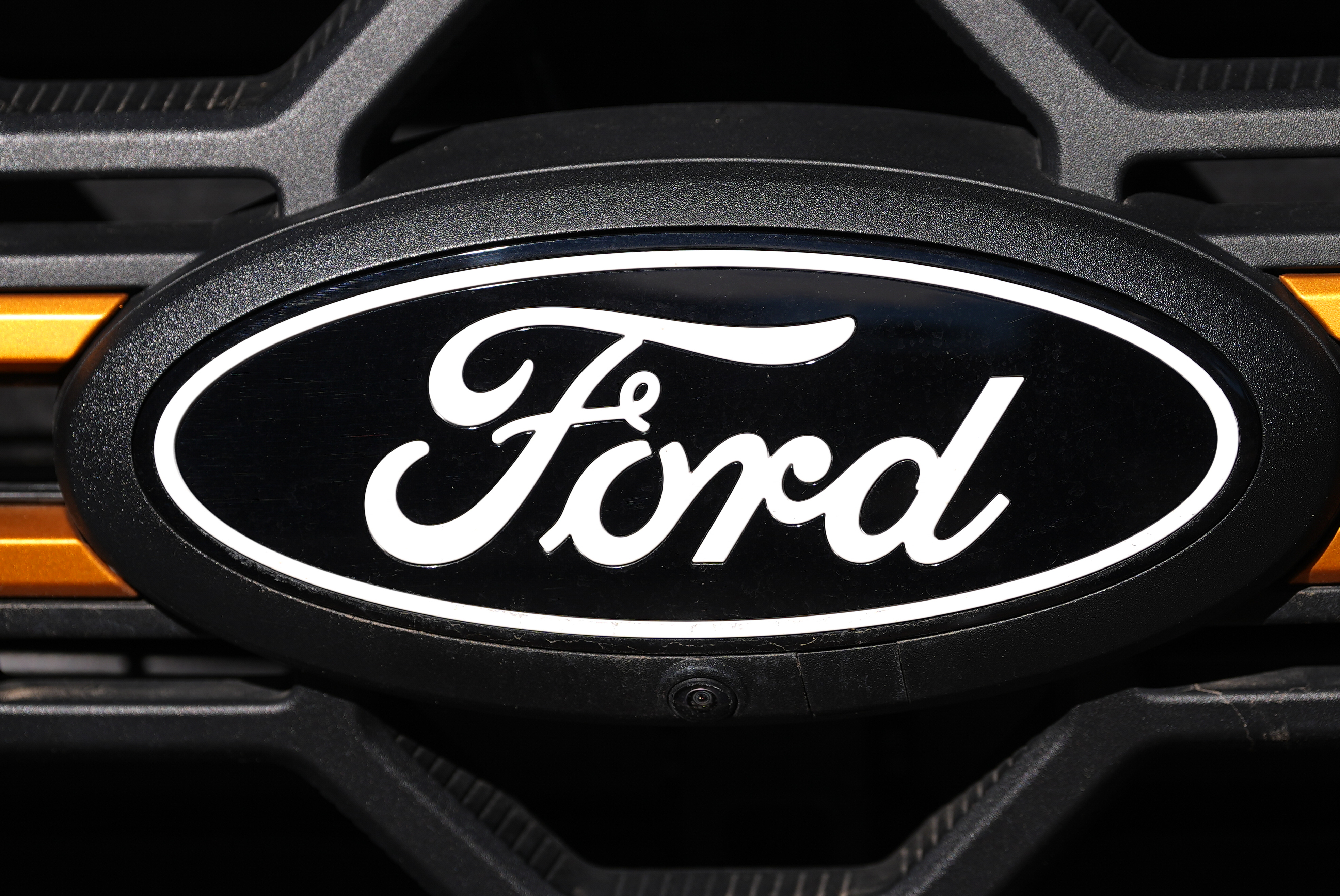 Ford oval logo on vehicle front grille with orange accent lighting