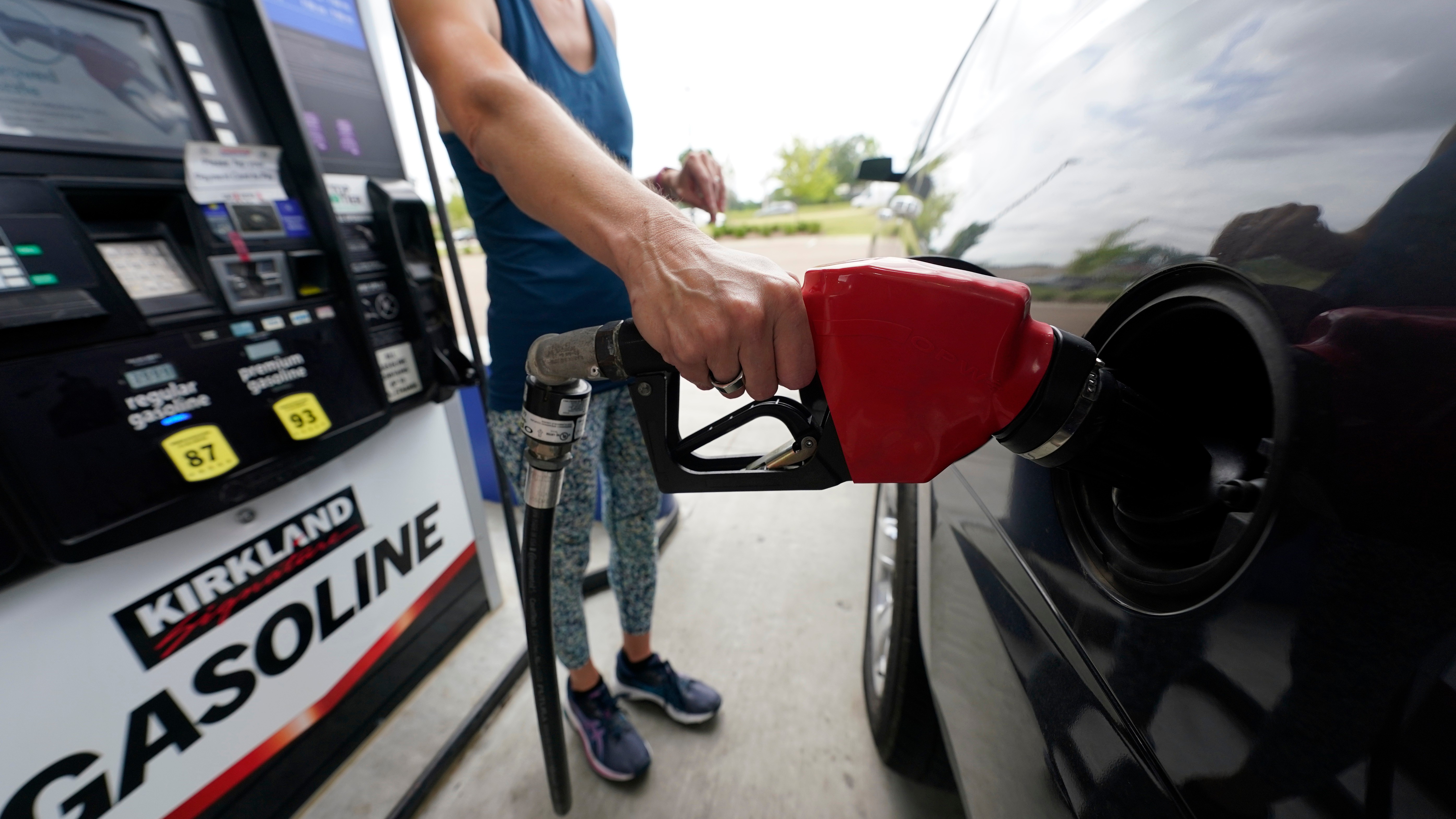 Person pumping red gasoline nozzle at Kirkland gas station pump