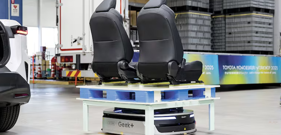 Black car seats displayed on blue and white platform with Geek+ branding in industrial warehouse setting