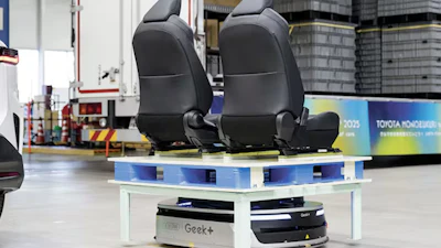 Black car seats displayed on blue and white platform with Geek+ branding in industrial warehouse setting
