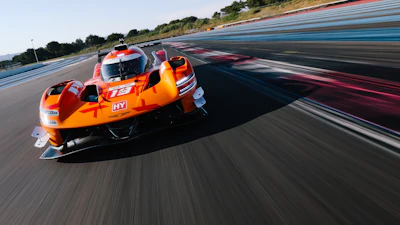 Orange jet ski racing at high speed on a professional racetrack with blue and red striping.