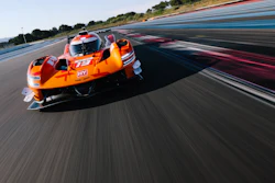Orange jet ski racing at high speed on a professional racetrack with blue and red striping.