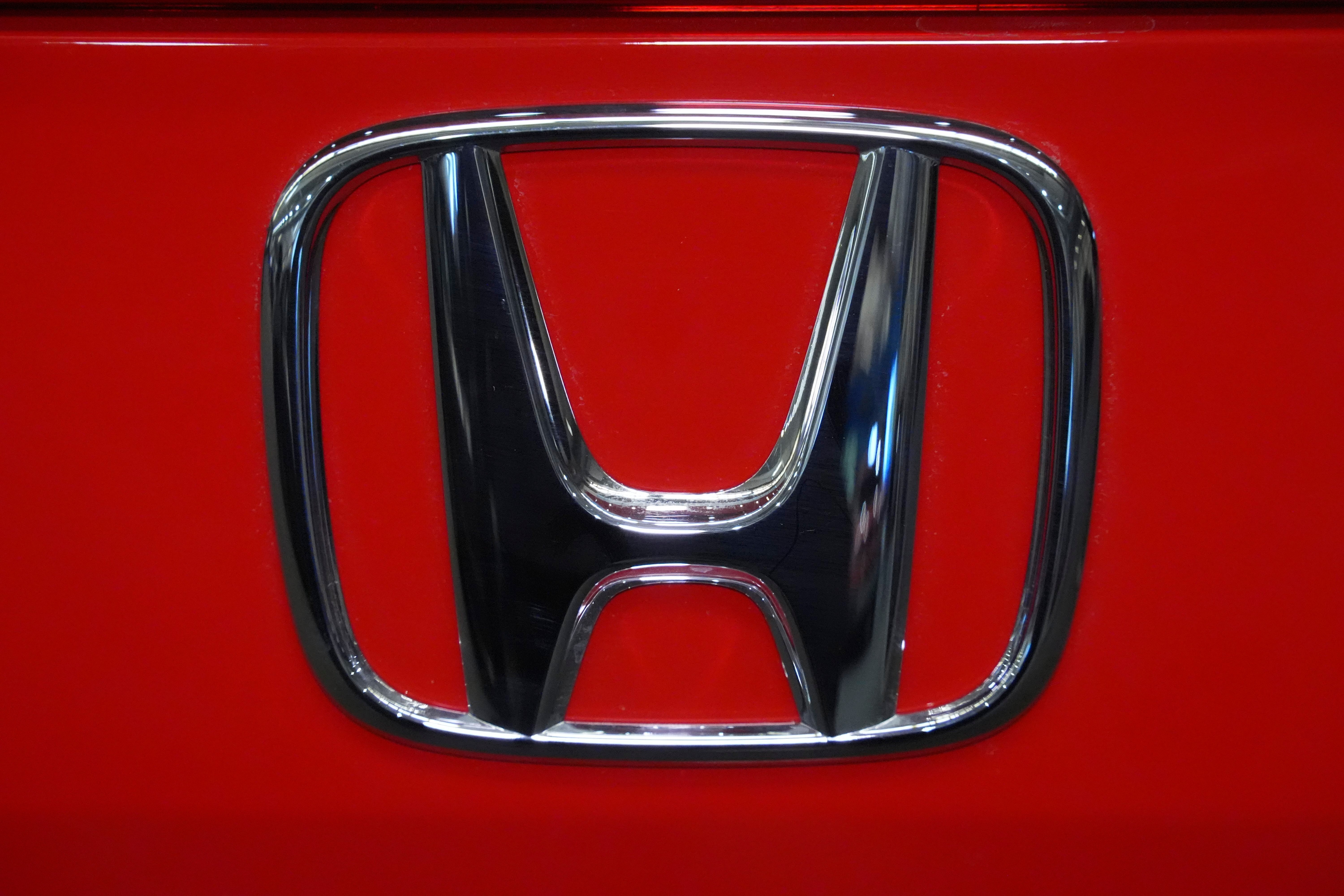 Honda logo emblem on red vehicle surface