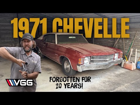 Man standing beside a restored 1971 red Chevrolet Chevelle in a garage setting