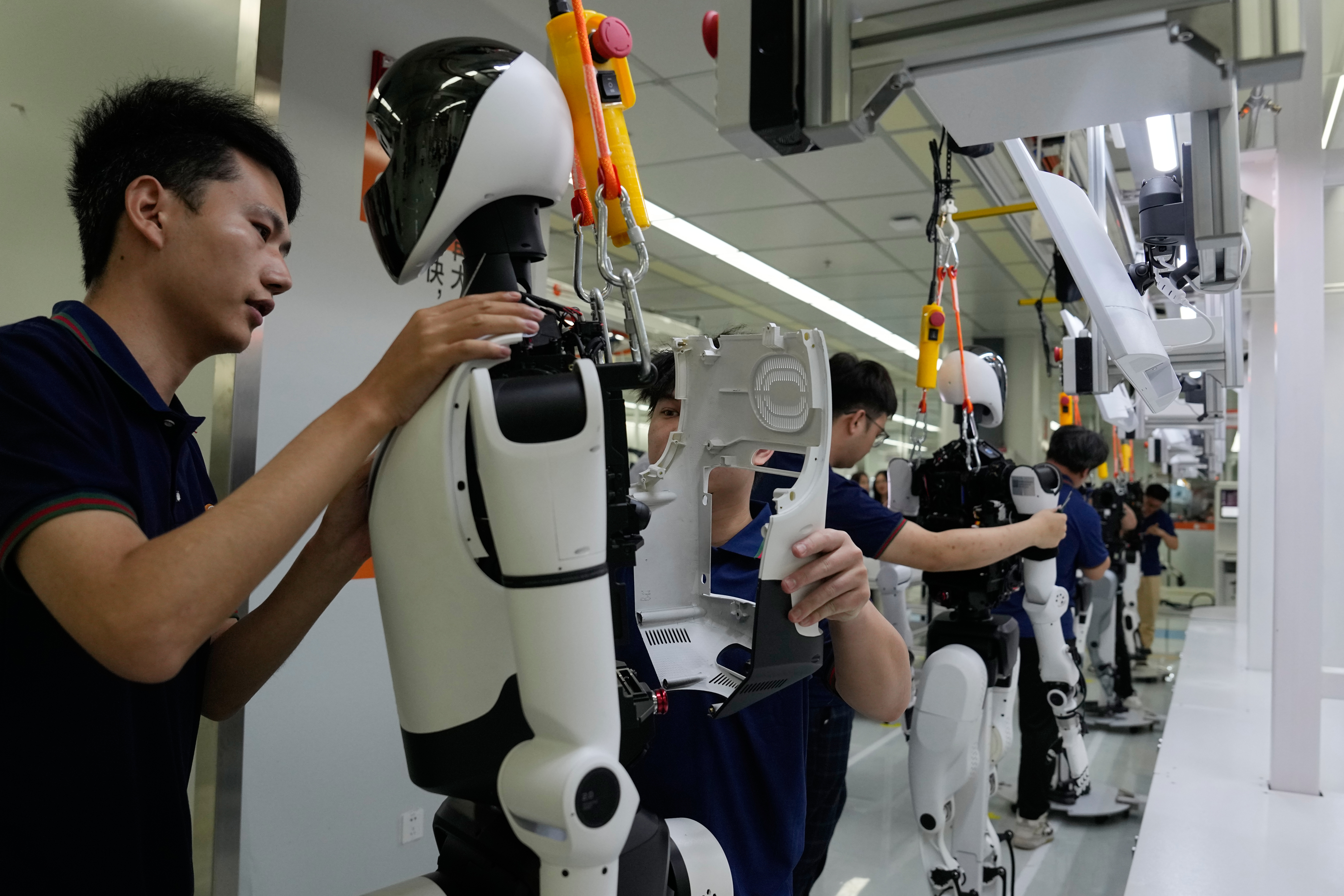 Technicians assemble and test a white humanoid robot in a laboratory facility