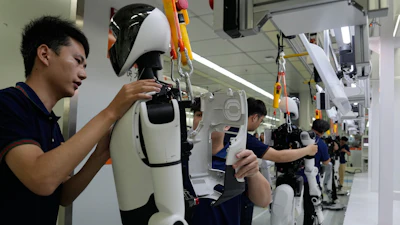 Technicians assemble and test a white humanoid robot in a laboratory facility